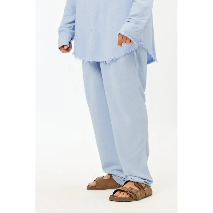 Person wearing a light blue outfit with brown sandals on a white background