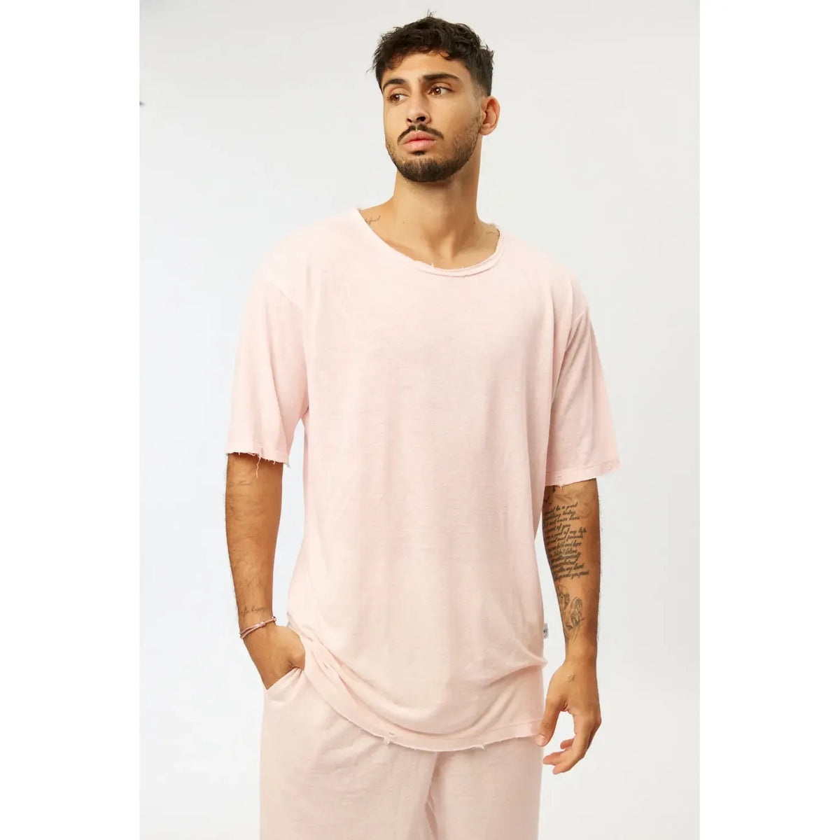 Man wearing a Nicki Soft Open Top in pink, with a relaxed fit and distressed edges