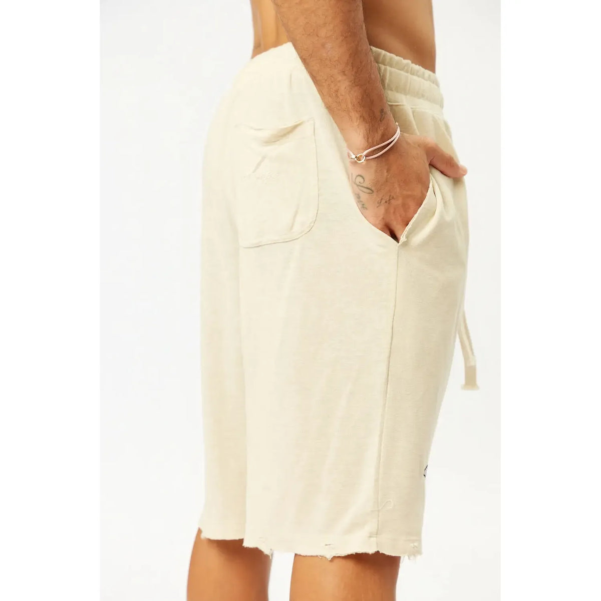 Base Shorts in Stone, close up of the shorts on a person, showing the pocket, drawstring, and distressed hem