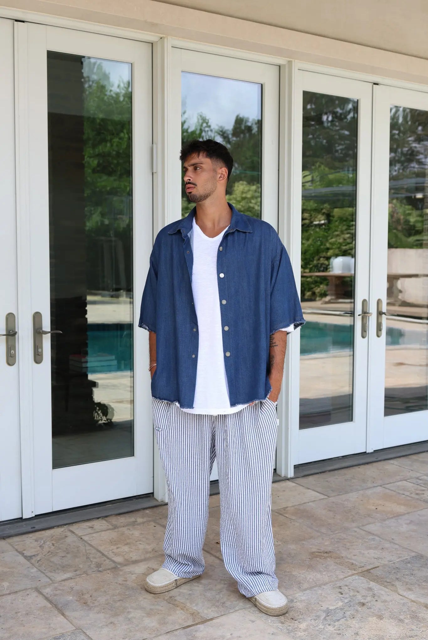 Man wearing Pure Oversized Linen Pants in blue and white stripes, a white t-shirt, and a blue denim shirt
