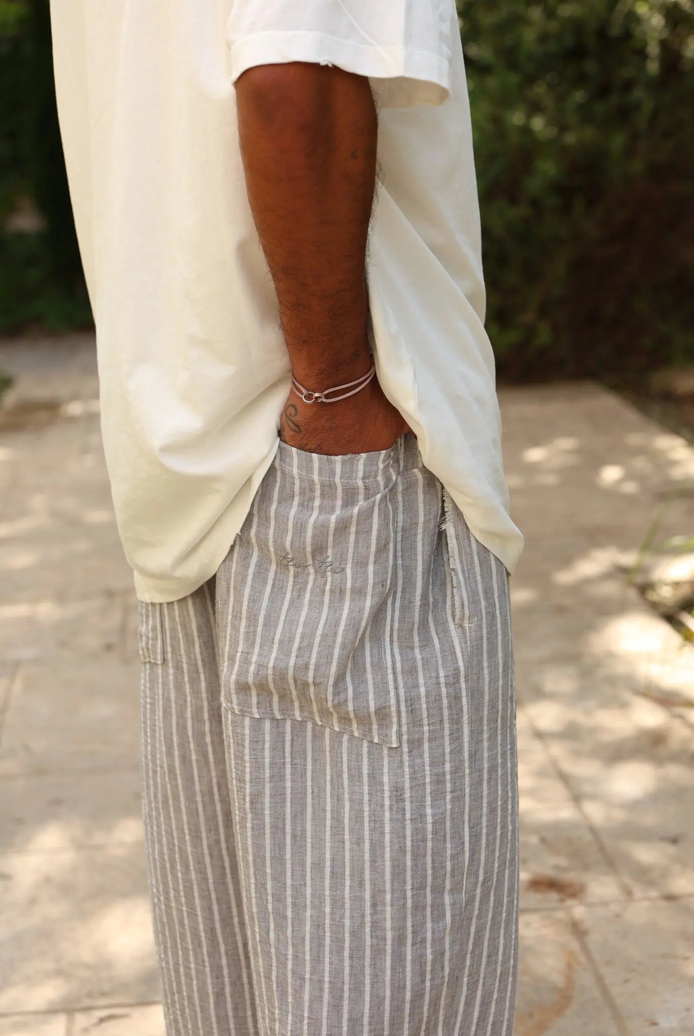 Pure Oversized Linen Pants in grey and white stripes, with a person's hand in the pocket