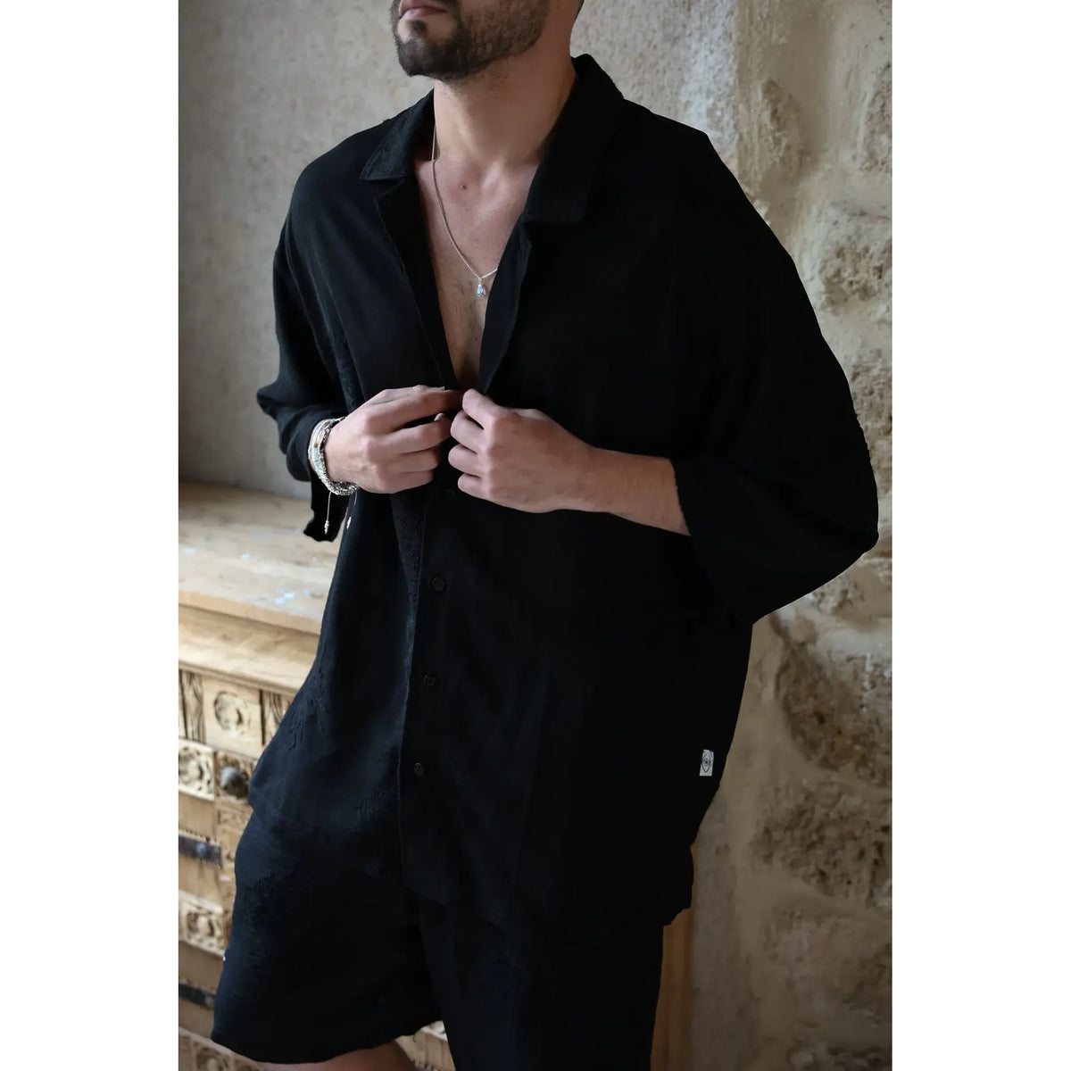 Man adjusting the buttons on a black SPARKS 3/4 Sleeve Button-Up Shirt