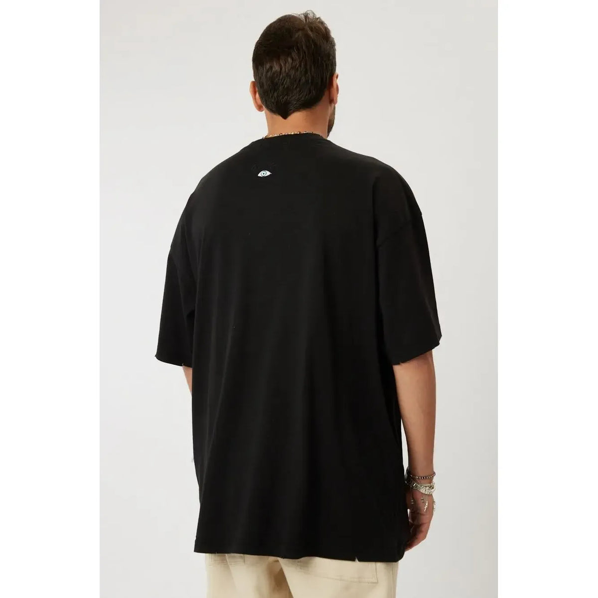 Back of a black Cotton T-Shirt with a small eye graphic on the neck