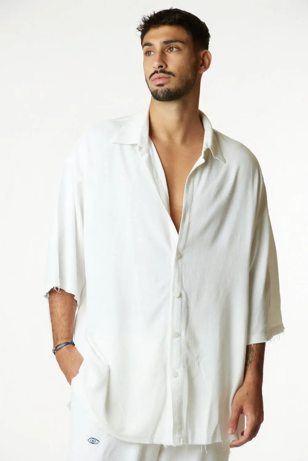 Man wearing a white oversized shirt against a plain background