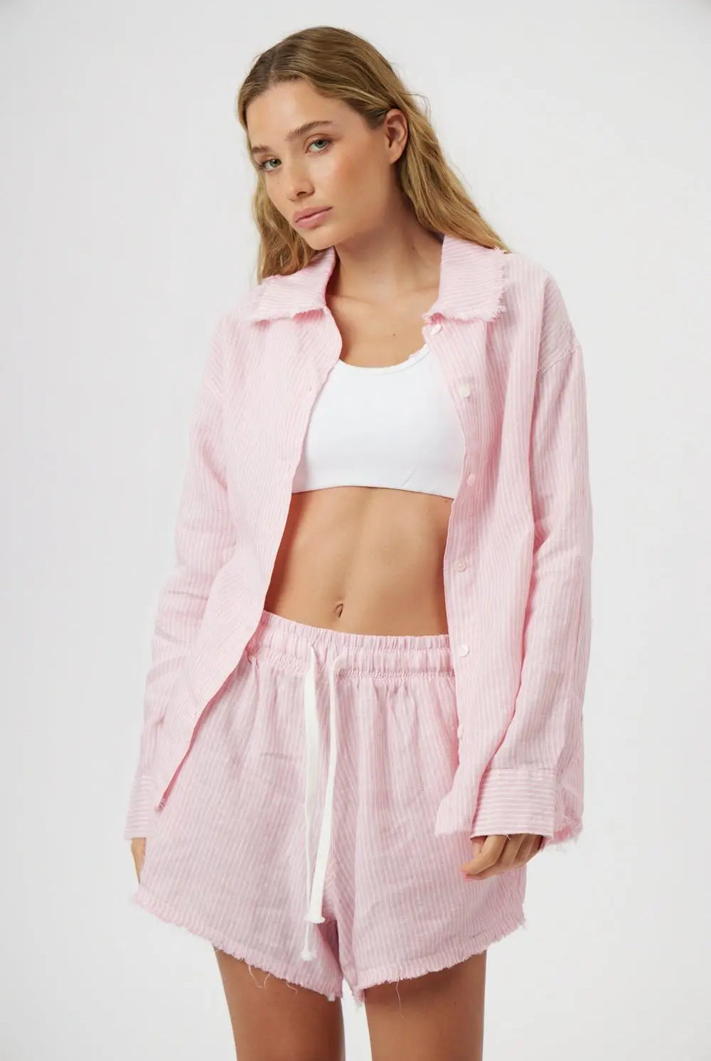 Woman wearing a pink textured shirt and shorts set on a white background