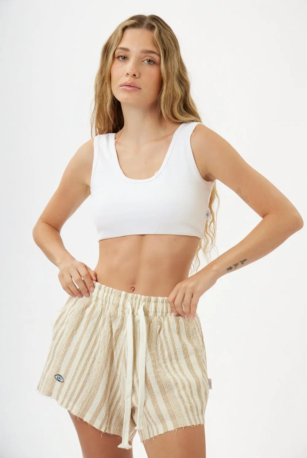 Pure Linen Women's Shorts in beige and white stripes, worn by a woman with a white crop top