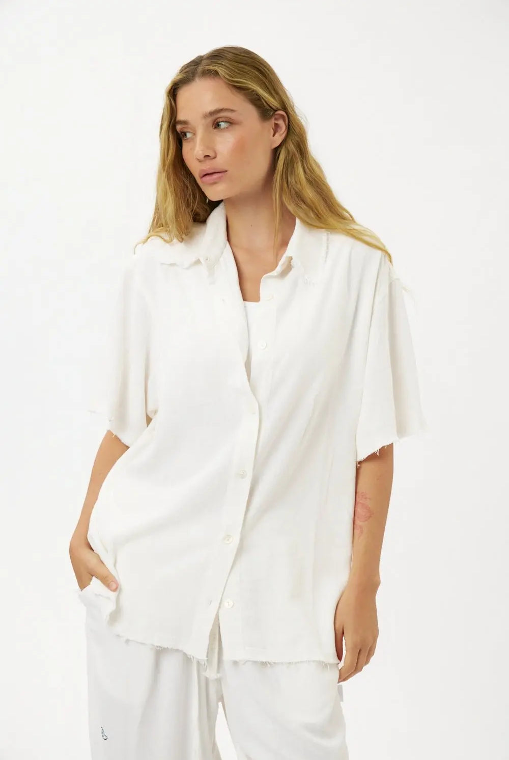 Woman wearing a white Soft Linen Short Sleeve Button-Up Shirt and matching white pants
