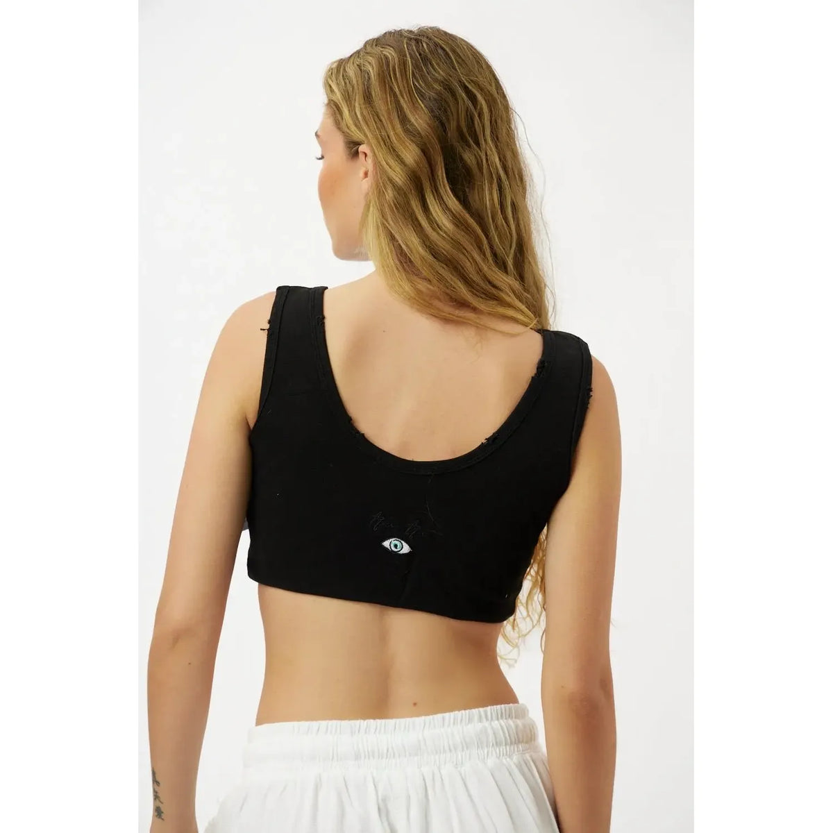 Back of a woman wearing an Essential Crop Top in black with an eye graphic