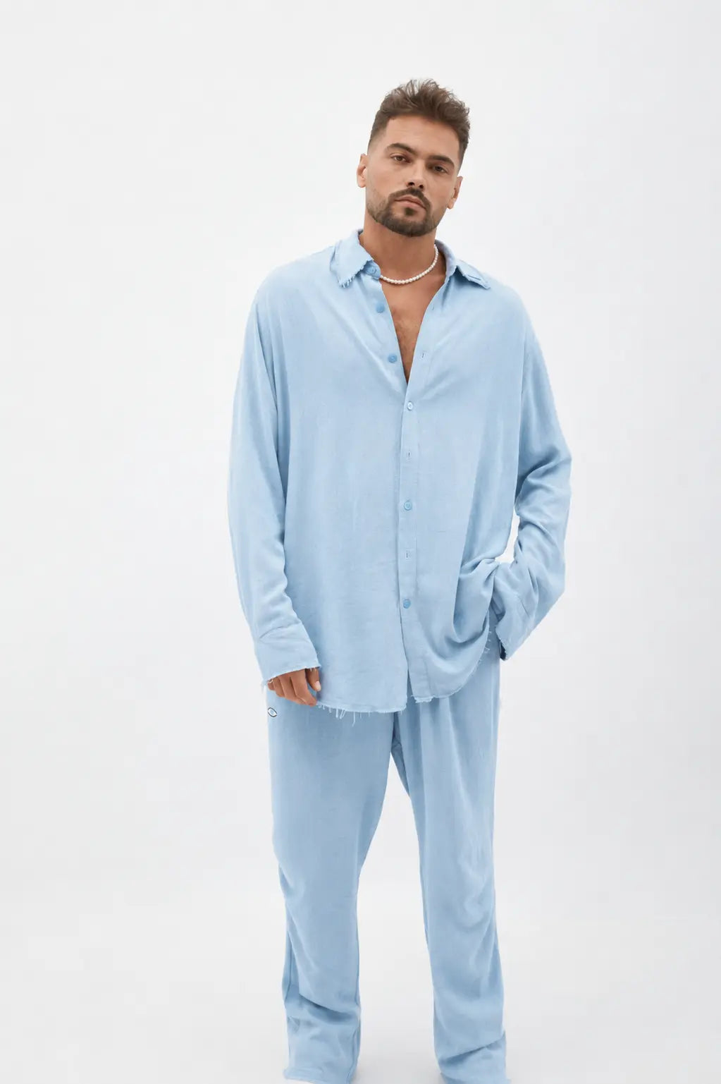 Man wearing a Soft Linen Long Sleeve Button-Up Shirt in Ice Blue with matching pants and a pearl necklace