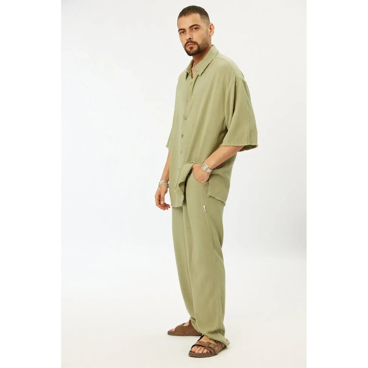 Man wearing a Soft Linen Short Sleeve Button-Up Shirt in green with matching green linen pants and brown sandals