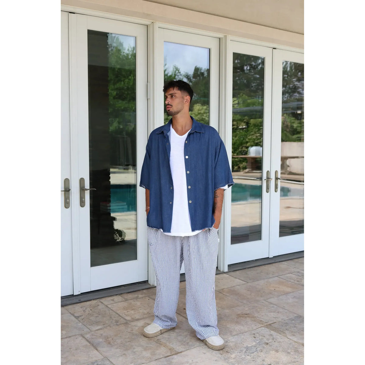 Man wearing Pure Oversized Linen Pants in blue and white stripes, a white t-shirt, and a blue denim shirt