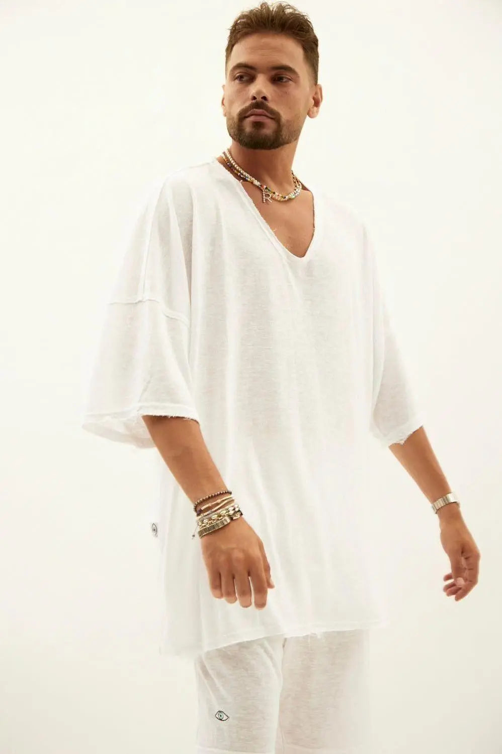 Man wearing a white oversized V-neck t-shirt and white shorts, accessorized with layered necklaces and bracelets, part of the BASIC SET - WHITE