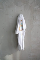 Cotton Single Elliptical Eye Blanket draped over a hook on a textured grey wall