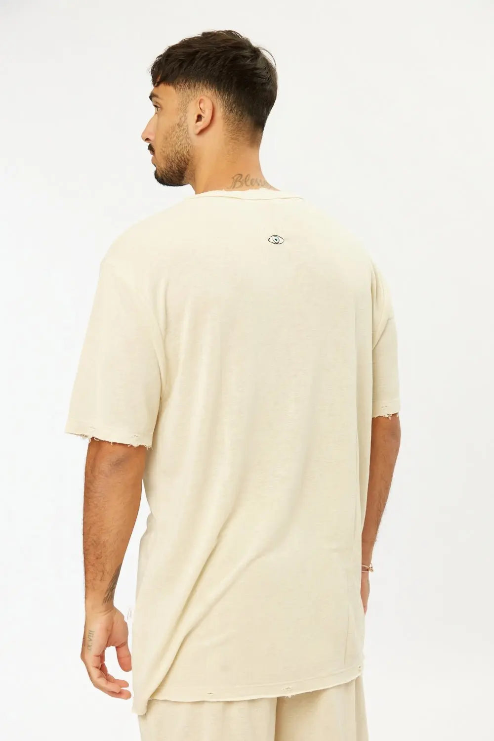 Man from behind wearing a TFU Soft Essential Tee in light stone with a small eye graphic on the back