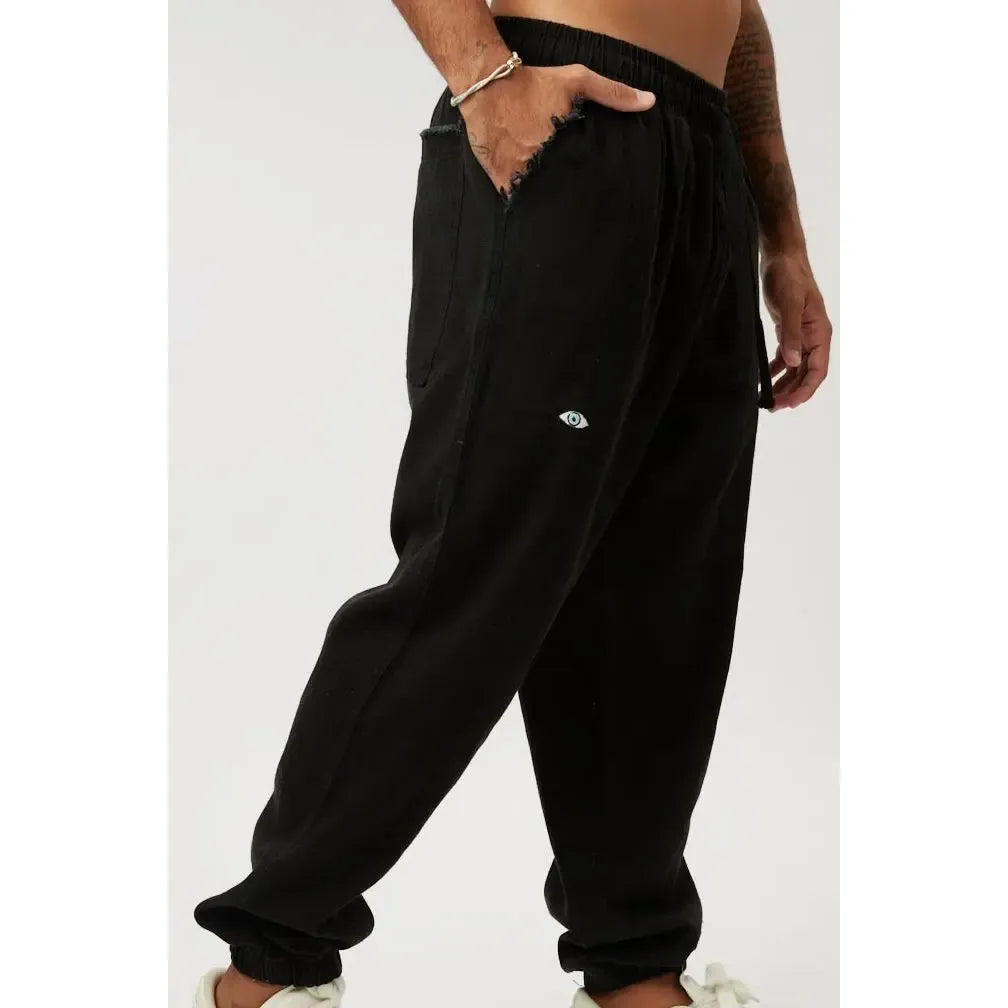 DC Elastic Waist Pants with Elastic Hem in black, featuring an eye logo and a frayed pocket