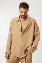 Man wearing a LUX CAMEL - SET, a camel-colored oversized button-up shirt and matching pants