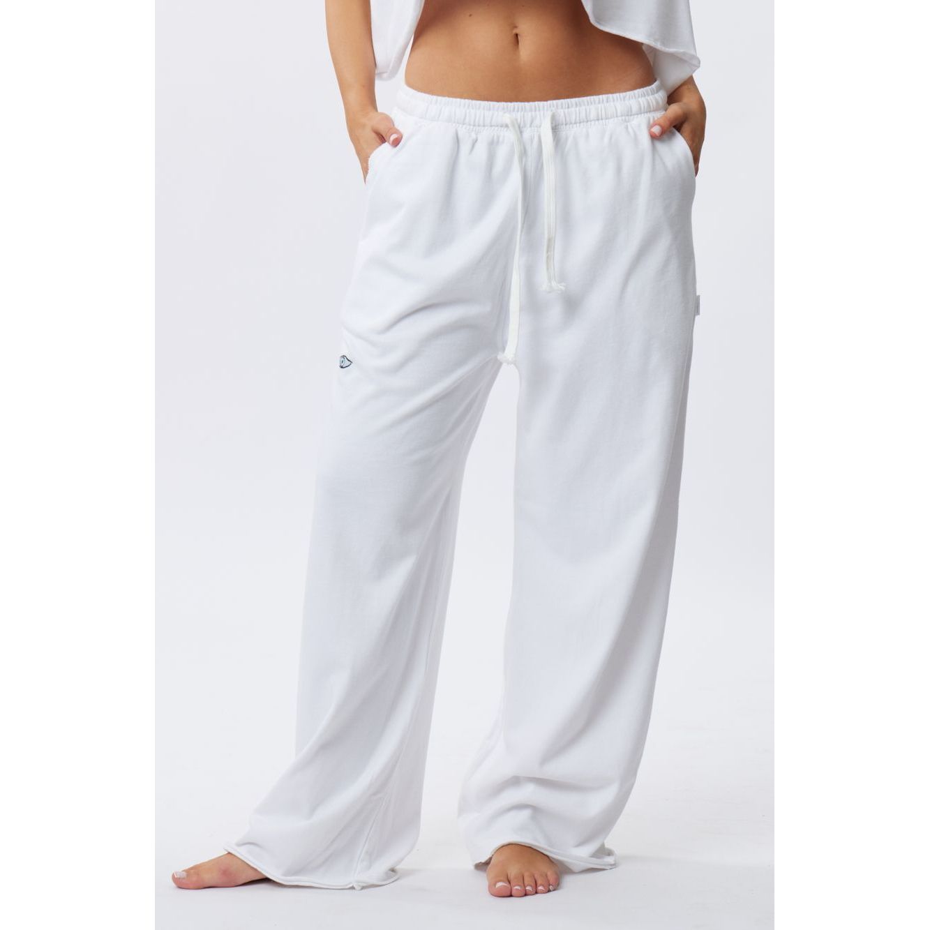 White wide-leg lounge pants with a drawstring waist and side pockets, shown on a model against a plain white studio background.
