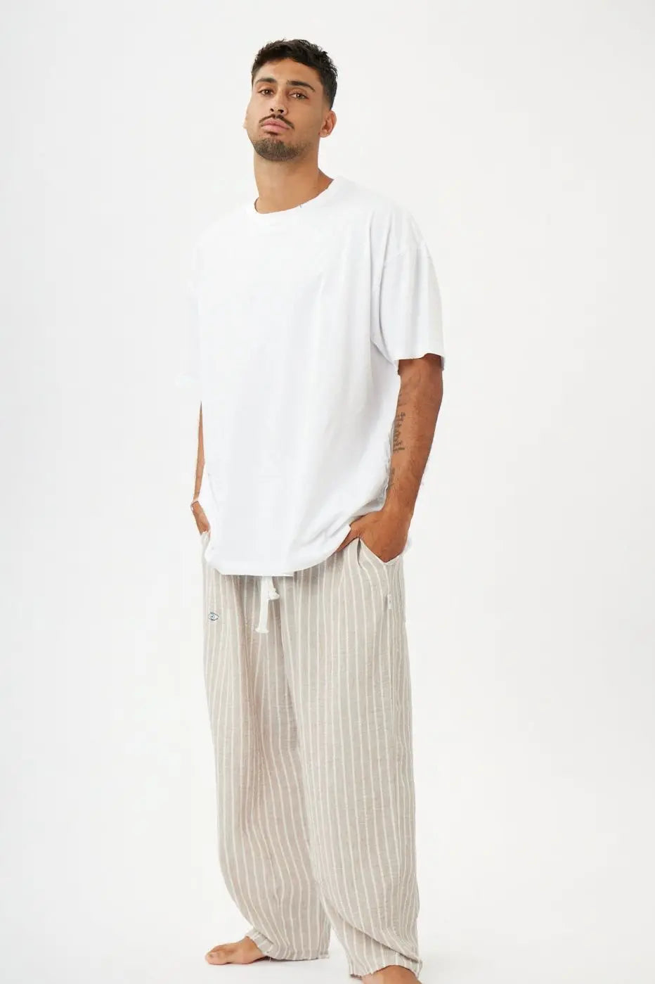 Man wearing Stone & White Stripes Linen Set, with oversized pants and a white cotton shirt