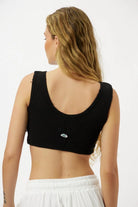 Back of a woman wearing an Essential Crop Top in black with an eye graphic