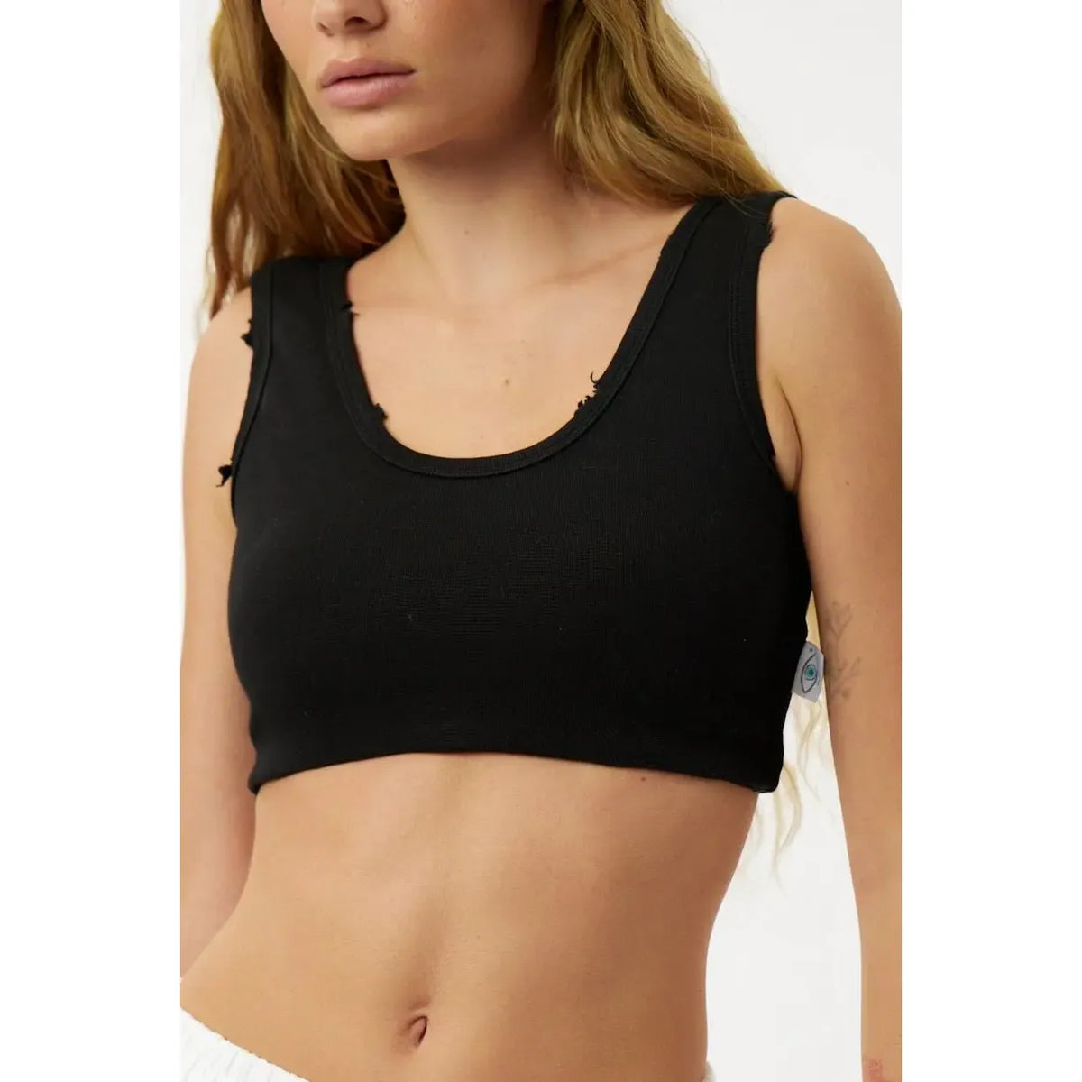 Black crop top worn by a person on a plain background