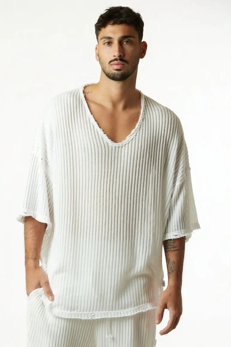 Man wearing a loose-fitting white shirt with a plain background