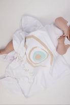 Baby covered by a white Cotton Single Elliptical Eye Blanket with a large eye graphic