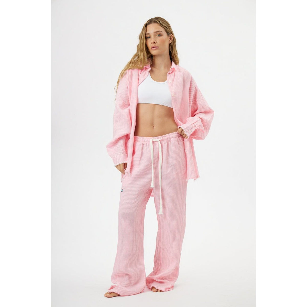 Woman wearing a pink tracksuit with a white top on a white background