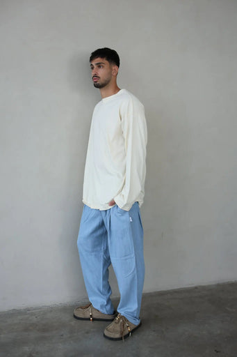 Man wearing Light Denim Pants with Belt and a long-sleeved cream shirt